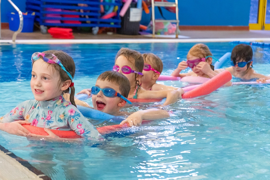 Children enjoying a Swim School lesson in the pool, developing confidence and water skills