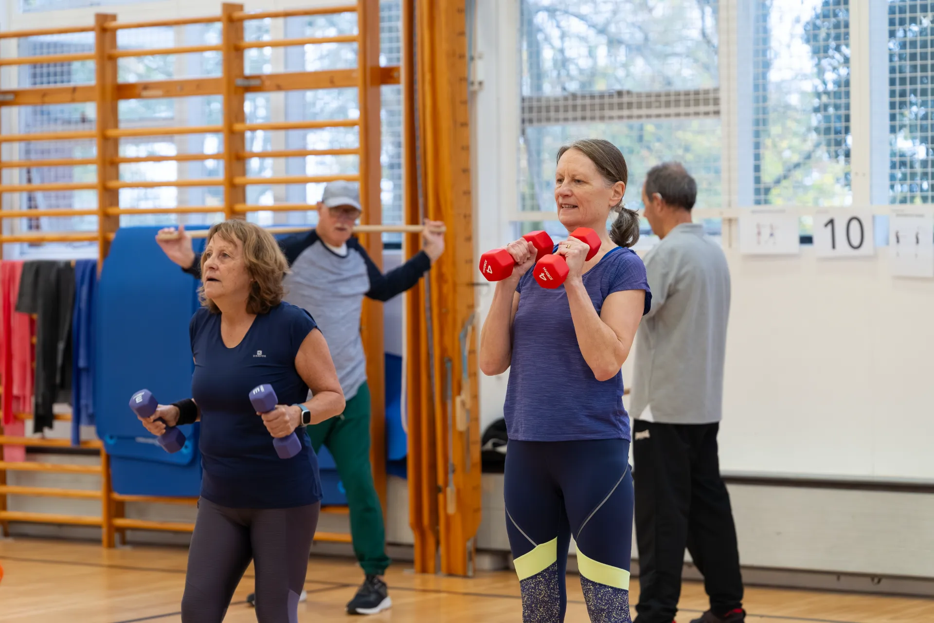 Older woman in a group fitness class using small gym weights